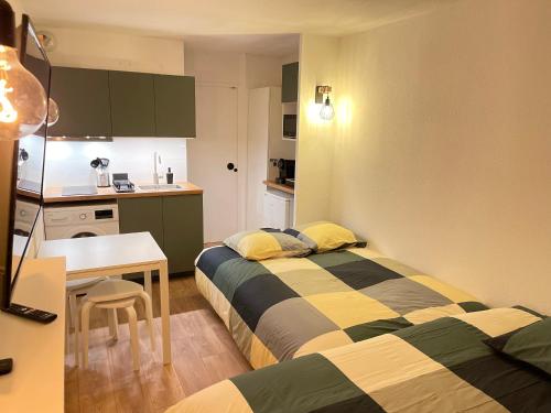 a room with two beds and a table and a kitchen at T2D Apartment - Suite TVR proche Disneyland Paris in Bussy-Saint-Georges