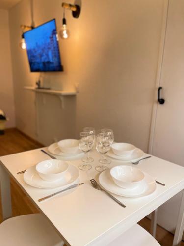 - une table avec des assiettes blanches et des verres à vin dans l'établissement T2D Apartment - Suite TVR proche Disneyland Paris, à Bussy-Saint-Georges