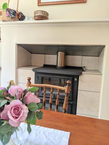 a fireplace with a black stove with a vase of flowers at Cottage in Uraidla in Uraidla