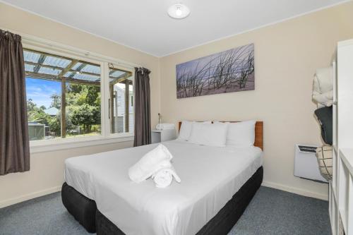 a bedroom with a large white bed with a window at Back of Beyond Cottage in Rotoiti