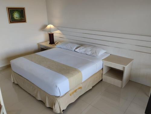 Queen Garden Hotel في باتورادن: غرفة نوم بسرير كبير وموقف ليلي