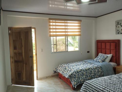 een slaapkamer met 2 bedden en een raam bij Imelda House in Ayangue
