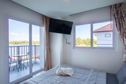 a bedroom with a bed and a window with a balcony at Mantra Beach condominium M116,M140 in Ban Phlong Sawai