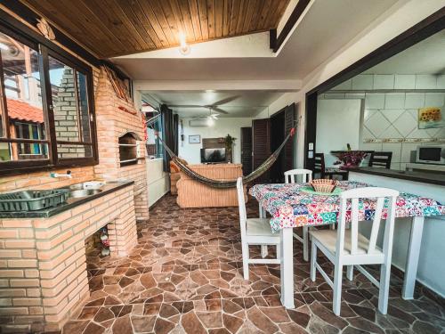 a dining room with a table and chairs and a kitchen at Casa 3 - Estrela Dalva, vista para o mar! in Farol de Santa Marta