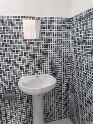 a bathroom with a sink and a tiled wall at Porto apartamento 6 in Porto Seguro