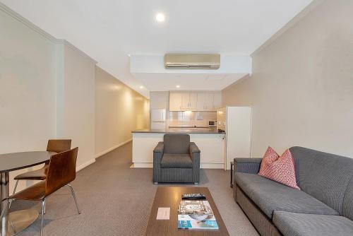 a living room with a couch and a table and a kitchen at Franklin Apartments in Adelaide