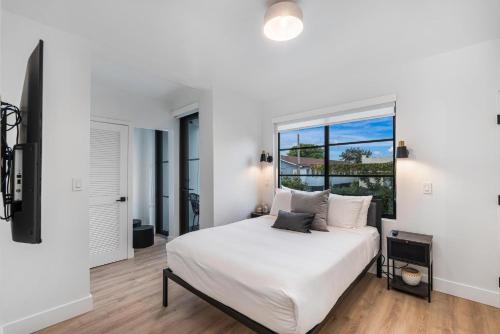 a white bedroom with a bed and a window at Lux Retreat By Renzzi in Miami