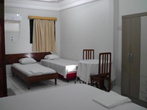 een kamer met 2 bedden en een tafel en stoelen bij HOTEL NEW´S BUSINESS in Macapá