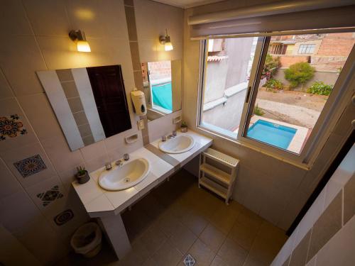 a bathroom with two sinks and a mirror and a window at Refugio del Turista in Tupiza