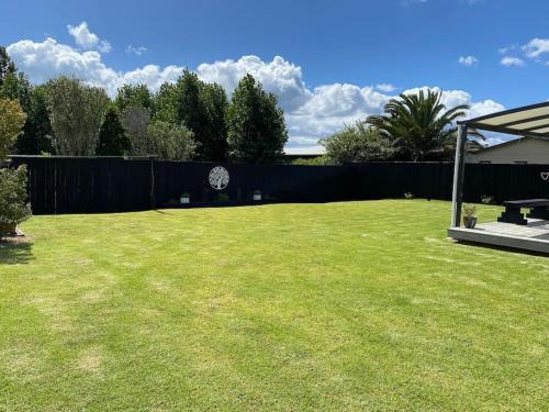 a yard with a fence and a grassy lawn at Whitianga Kiwi Bach in Whitianga