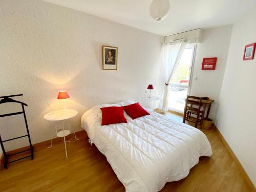 une chambre avec un lit blanc avec des oreillers rouges dans l'établissement Appartement Charmant avec Garage à 400 m de la Plage - FR-1-92-738, à Les Sables-dʼOlonne