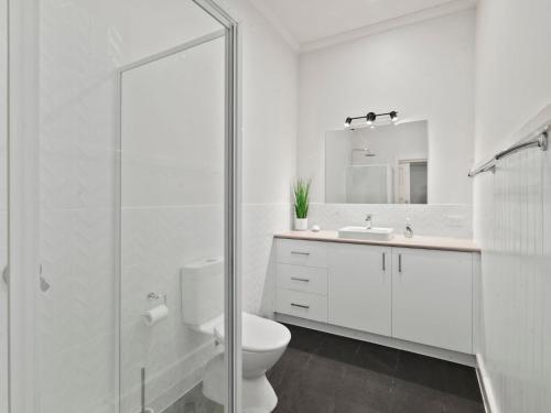 bagno bianco con servizi igienici e lavandino di Piper St Cottage a Yarrawonga