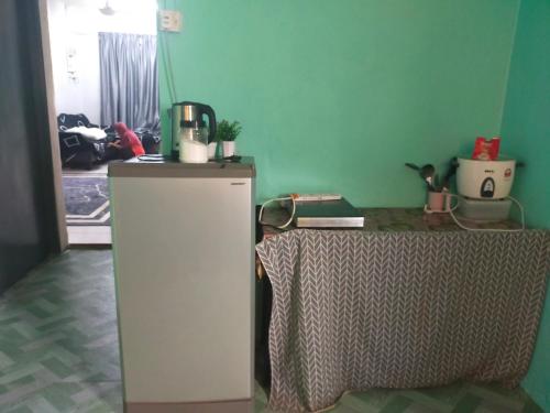 Cette chambre comprend un petit réfrigérateur et une table. dans l'établissement Homestay Sri Awana, à Alor Setar