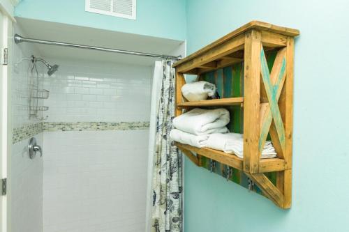 a bathroom with a wooden shelf next to a shower at Bayside Cutie at Bayside Bungalow in Anna Maria