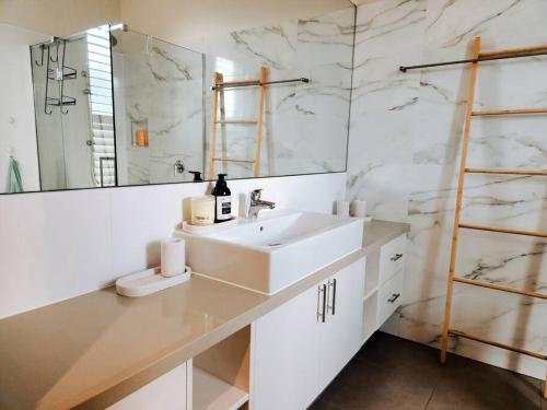 Baño blanco con lavabo y espejo en Hillcrest Harmony: Luxury in Westmeadows 20% OFF en Melbourne