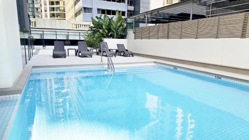 ein großer Pool mit Stühlen und ein Gebäude in der Unterkunft Oaks Brisbane on Charlotte Suites in Brisbane