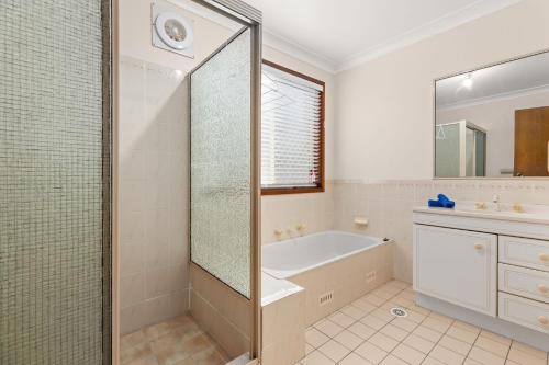 a bathroom with a shower and a tub and a sink at Daybreak by Experience Jervis Bay in Vincentia