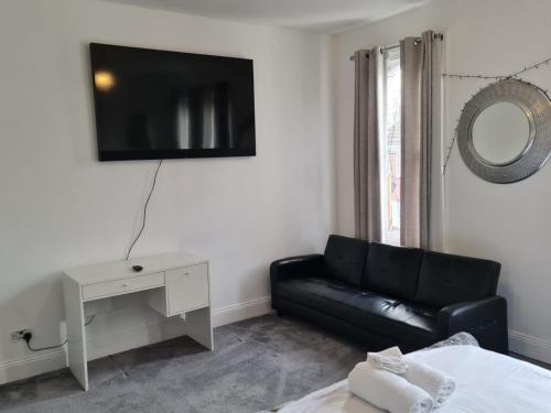 ein Wohnzimmer mit einem Sofa und einem TV an der Wand in der Unterkunft Three bedroom House in London
