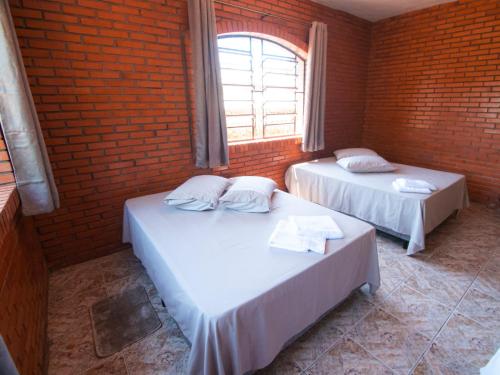 2 camas en una habitación con una pared de ladrillo en Residencial Colling en Canela