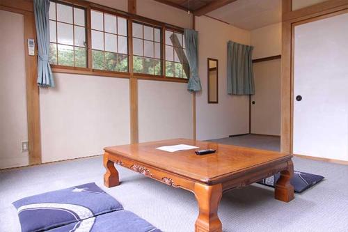 een kamer met een houten tafel in een kamer bij ロッヂとんや in Seki