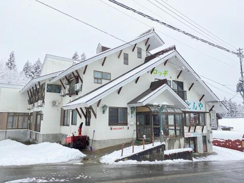 ein weißes Gebäude mit Schnee davor in der Unterkunft ロッヂとんや in Seki