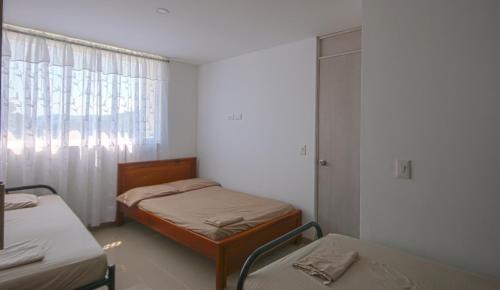 a small room with two beds and a window at Apto Di Sole Santa FeAntioquia in Santa Fe de Antioquia