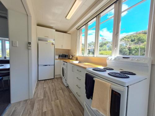 cocina con fogones y nevera blanca en Surfers Dream - 1 bedroom en Dunedin