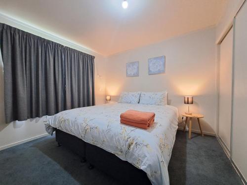 Un dormitorio con una cama con una manta naranja. en Surfers Dream - 1 bedroom en Dunedin
