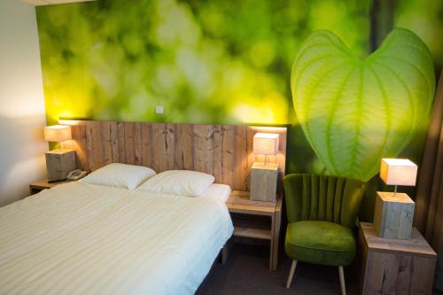 a bedroom with a bed and a green chair at Forest Hotel in Den Helder