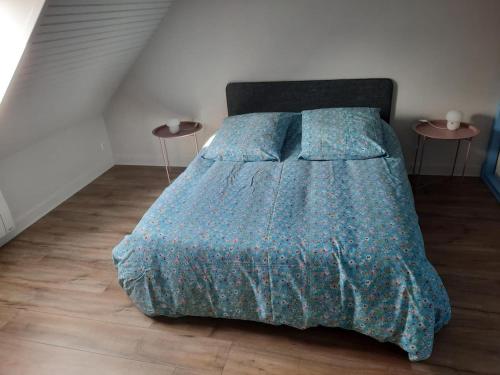 a bedroom with a bed with a blue comforter and two tables at Gîte spacieux avec grand jardin, à proximité de Vichy et attractions, tout confort inclus - FR-1-489-486 in Rongères