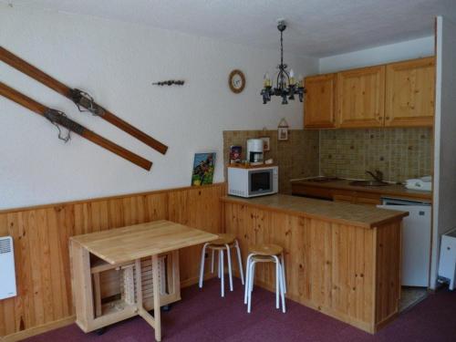 - une cuisine avec des placards en bois, une table et des chaises dans l'établissement Studio Les Orres, 1 pièce, 4 personnes - FR-1-322-583, aux Orres