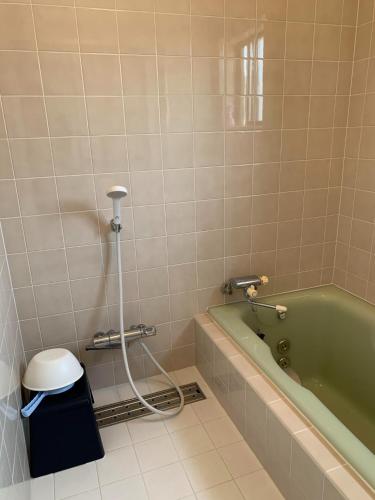 a bathroom with a green tub and a trash can at Ao to Yuuhi - Vacation STAY 34462v in Tateyama