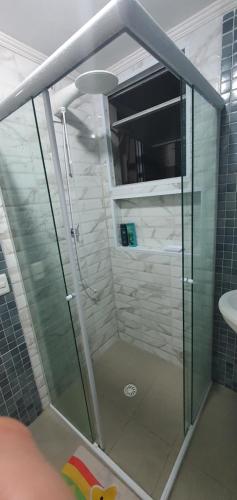 a glass shower in a bathroom with a sink at Condomínio Itaparica III in Guarujá