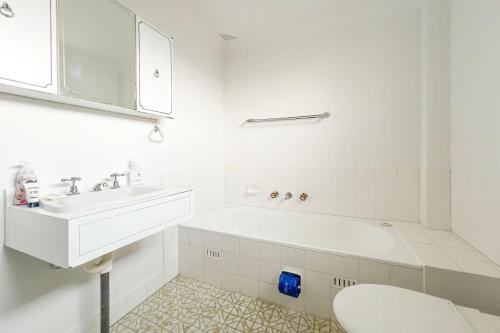 a white bathroom with a tub and a sink at Seabreeze 3 in Tuncurry