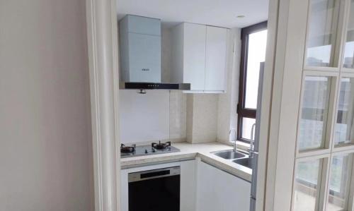 a kitchen with white cabinets and a sink and a window at 新虹桥首府 in Shanghai