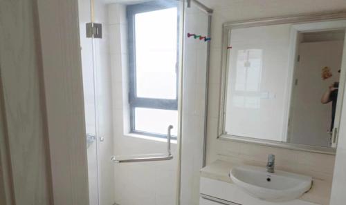 W białej łazience znajduje się umywalka i lustro. w obiekcie 新虹桥首府 w Szanghaju