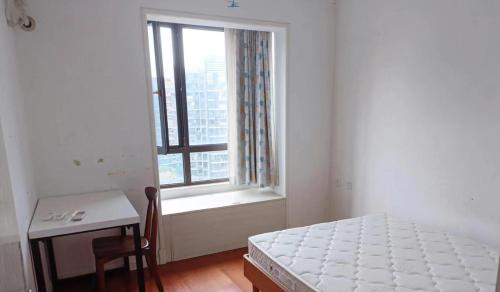 a bedroom with a bed and a table and a window at 新虹桥首府 in Shanghai