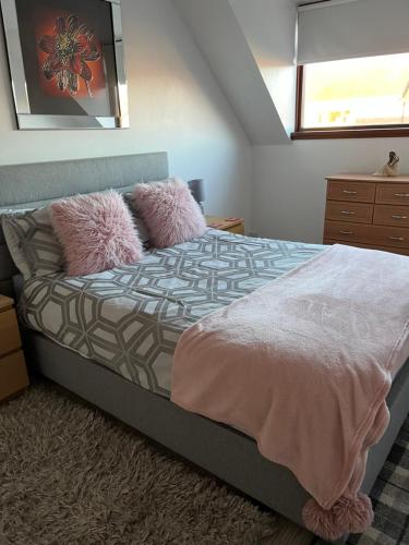 a bedroom with a bed with pink pillows and a window at No 22 in Banff