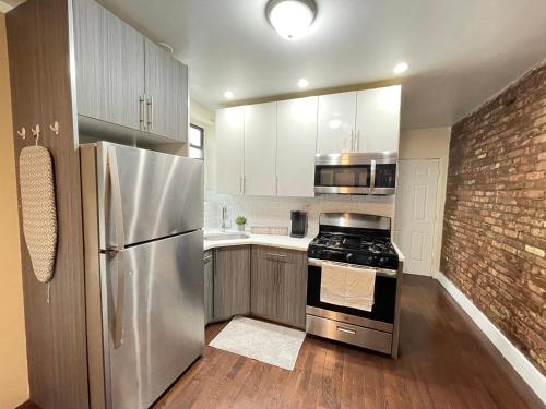 a kitchen with stainless steel appliances and a brick wall at Unique Three bedroom w/ workspace in Brooklyn