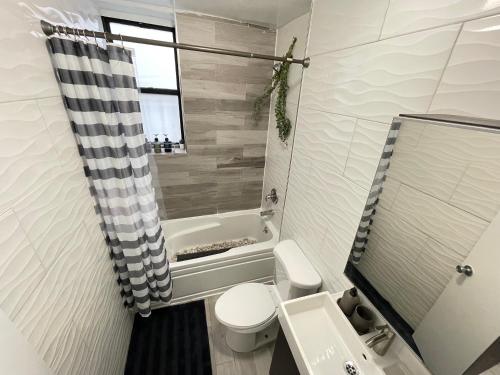 a bathroom with a toilet and a sink and a tub at Unique Three bedroom w/ workspace in Brooklyn