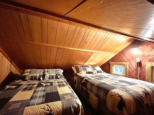 two beds in a room with a roof at O Me, O Mio Cabin near the AuSable River in Mio