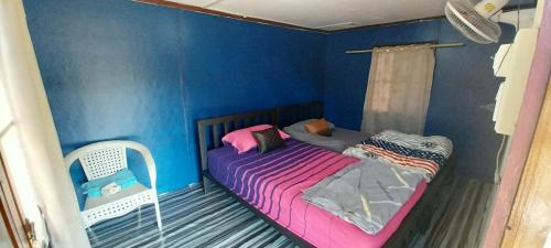 a small bedroom with a bed and a blue wall at Scorpion Wings Eco-Resort in Ban Na Nga