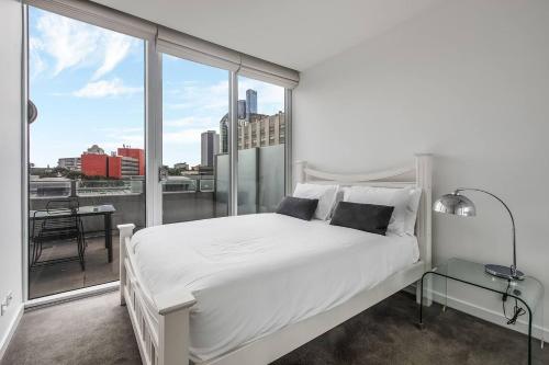 a bedroom with a white bed and large windows at 'Swanston Central' Wellness-infused City Living in Melbourne