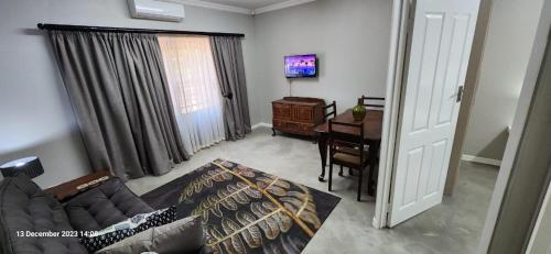 ein Wohnzimmer mit einem Sofa und einem Tisch in der Unterkunft Cottage Rose in Bloemfontein