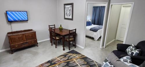 a living room with a table and a room with a bed at Cottage Rose in Bloemfontein