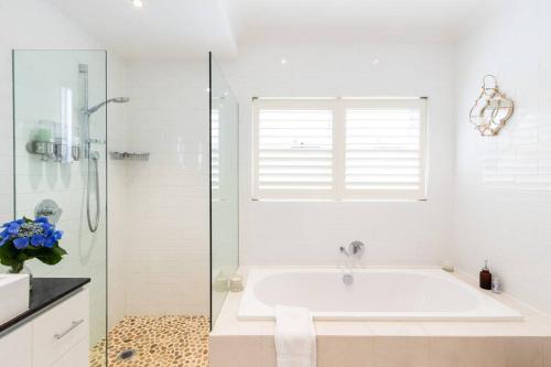 uma casa de banho branca com uma banheira e uma janela em Sealoc - Luxury beach house - by the sea em Freshwater