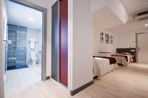 a bedroom with a bed and a bathroom at Hotel Ferramenteiro de Portomarin in Portomarin