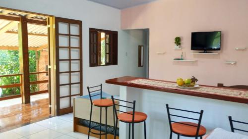 a kitchen with a bar with stools and a tv at Cantinho do Sossego - Sertão da Praia da Fazenda in Ubatuba