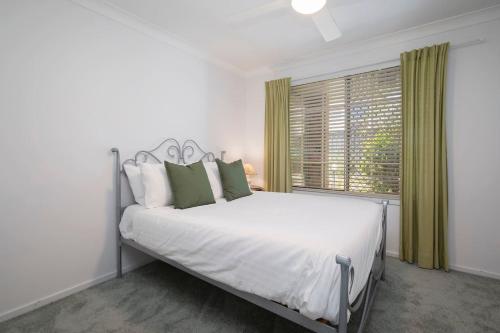 a white bedroom with a large bed and a window at 'The Elizabeth' A Romantic Garden Retreat for Two in Newcastle