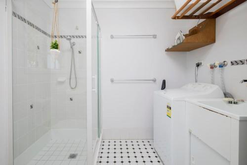 a white bathroom with a shower and a sink at 'The Elizabeth' A Romantic Garden Retreat for Two in Newcastle